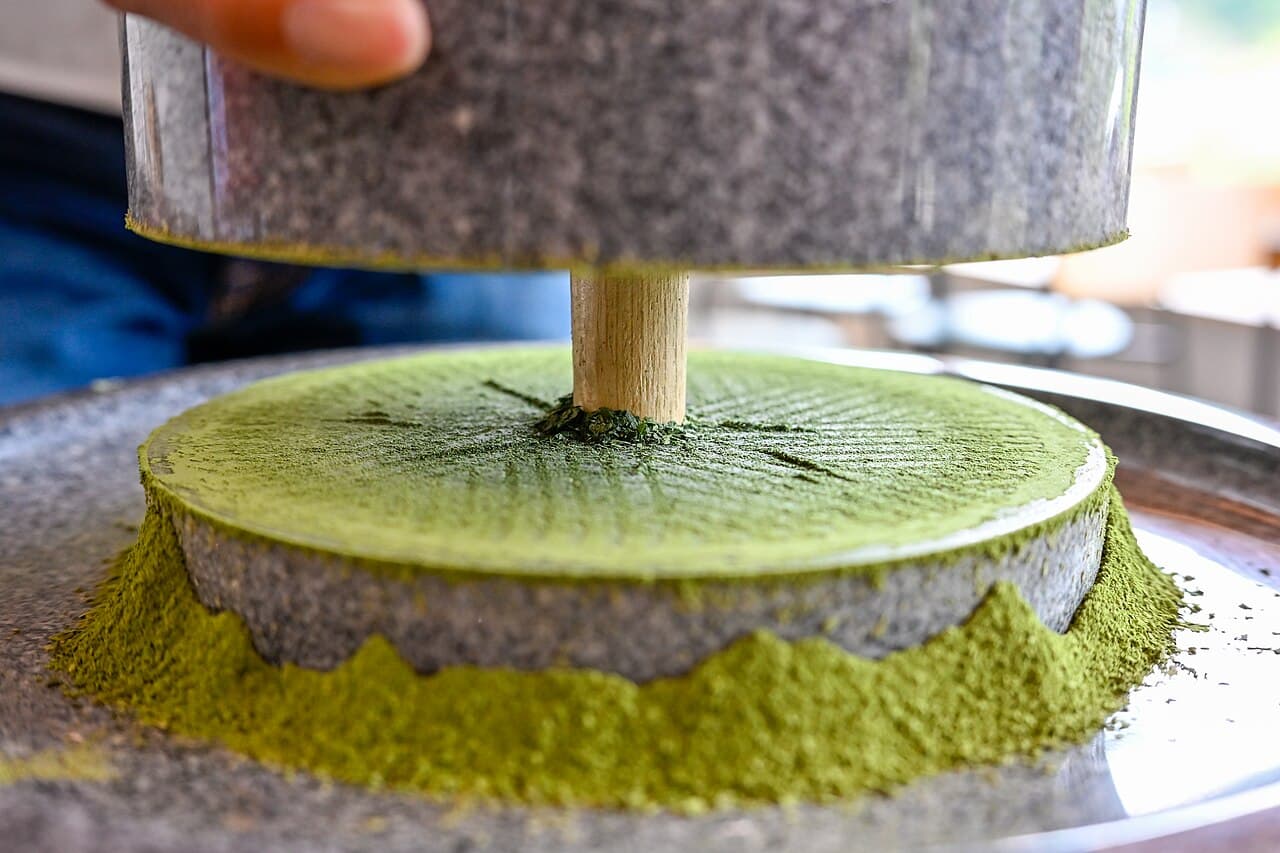 A traditional granite stone mill grinding tencha leaf into fine matcha powder — the raw material whose cost underlies every price-per-gram figure in this comparison