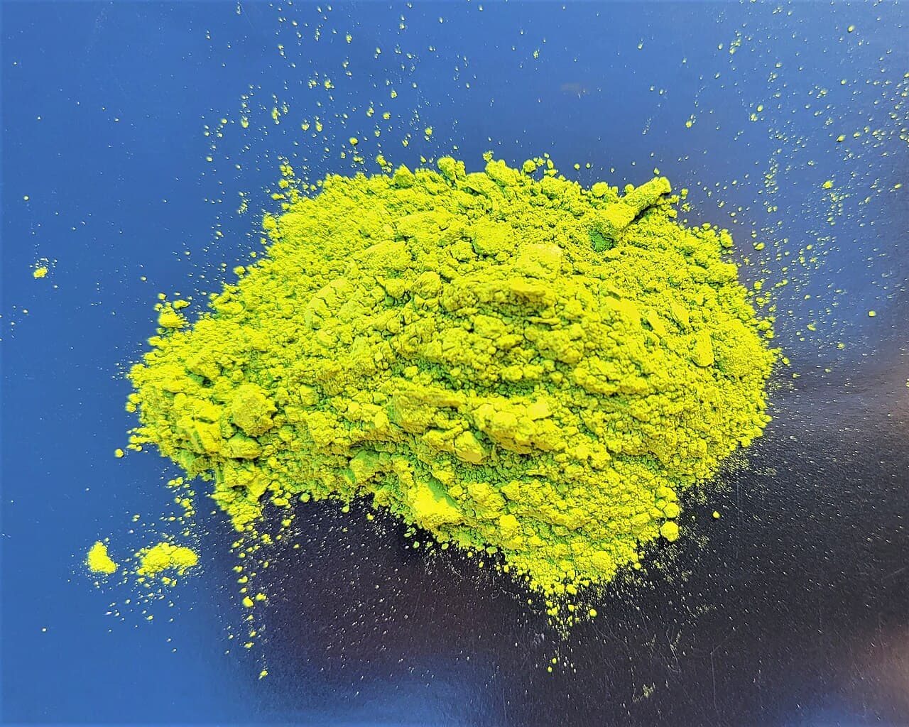 Fine bright-green matcha powder mounded on a dark surface
