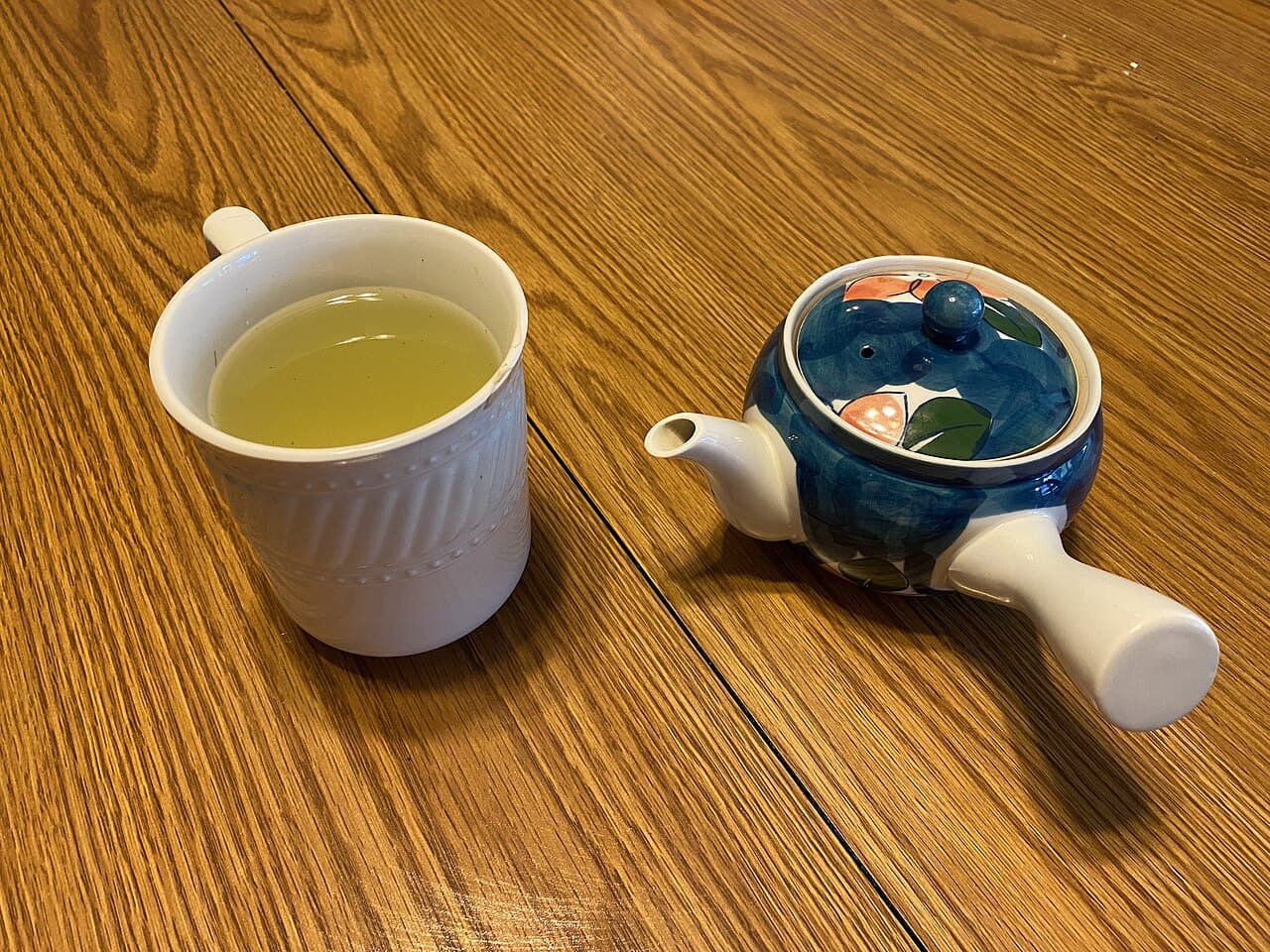 Steeped gyokuro in a white mug beside a kyusu teapot