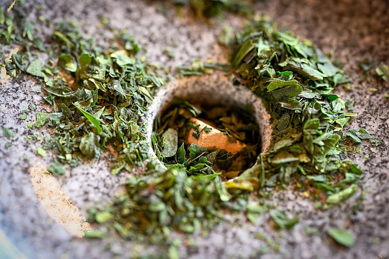 Tencha leaves being ground into matcha on a traditional stone mill in Uji — the raw material at the center of Japan's 2026 tea-price reporting